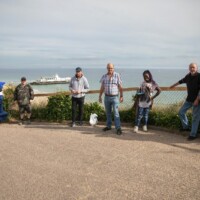 Group of participants standing along a fence, overlooking the beach and ocean.