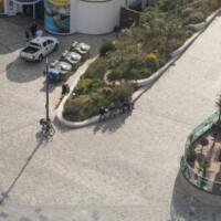 Photo from high up, taken of a group of people sat on a stone ledge.