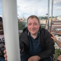 Jack smiling and sat with other participants in a gondola as it goes up and around.