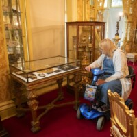 A participant in a mobility scooter looking at a display case.