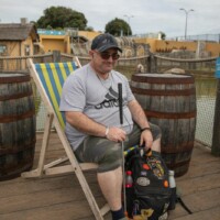 Kev sat down on a folding beach chair, smiling and holding a golf club.