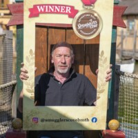 Gary holding up a photo frame at an outdoor crazy golf place.