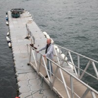 Gary standing on a bridge leading to a temporary pier going into the sea.