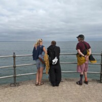 Rachel and two participants standing by some railings overlooking the ocean.