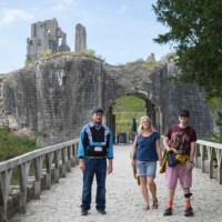 Rachel and two participants standing on a bridge leading to an old castle attraction.