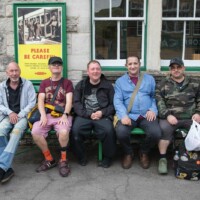 A group of participants sat on a green bench together outside the train station.