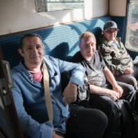 Rob, Jack, and Kev sitting on seats in a cabin on the train.