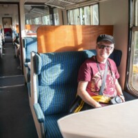 Participant sat on a seat on the train, smiling at the camera.