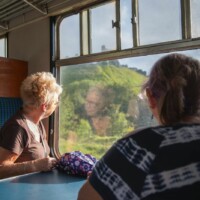 Helen and Gill sat at a table on the train, looking out the window and admiring the scenery.