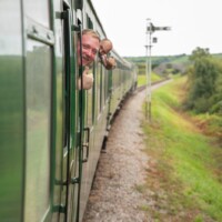 A photo taken of the train in motion, with two participants leaning their heads out of the windows and smiling at the camera.