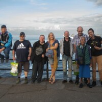 A group of participants lined up against the railings, with the ocean behind them.