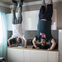 Two participants posing in the 'Upside Down House'. They're pretending to handstand on a kitchen countertop.