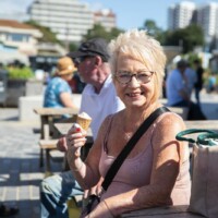 Helen, a participant, sat down on a wooden bench at the seaside eating an ice cream.