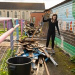 Young person picking up a piece of wood from a pile to take away at St James City Farm.