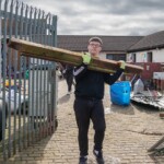 Young person carrying out some wood from demolishment work going on inside St James City Farm.