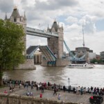 A photo of Tower Bridge, with lots of people leaning against the rails overlooking the Thames.