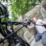 A participant on their knees, pretending to be stabbed by a black sculpture soldier.